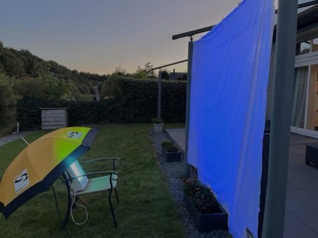 Attracting moths with a sheet and a face tanner. The umbrella protects against the rain. 