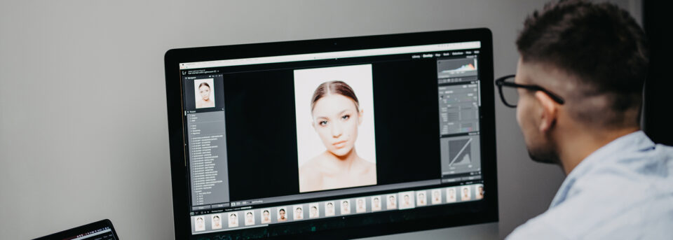 Photographer editing a portrait in Lightroom on a desktop monitor using RAW noise reduction software