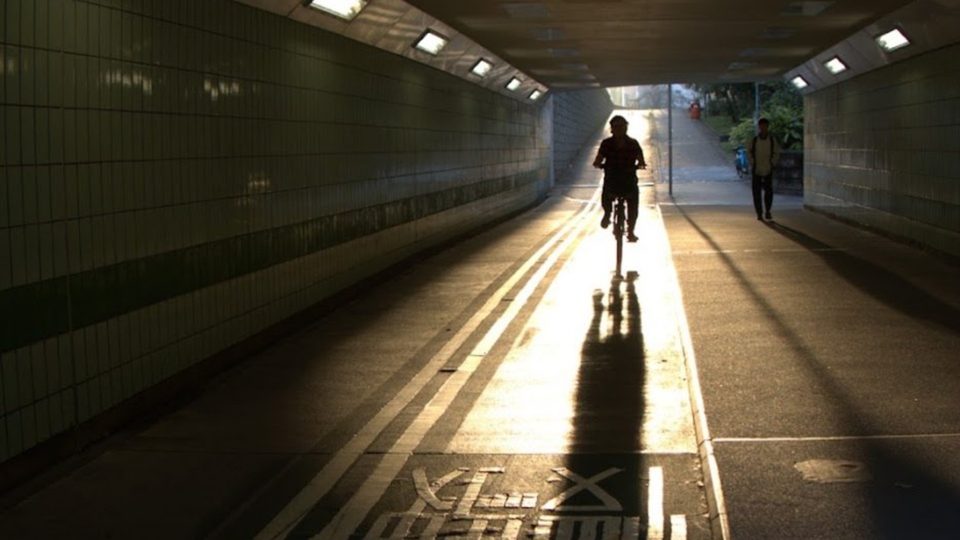 Cyclist riding through a tunnel toward sunlit pavement, before the Urban Pop LUT