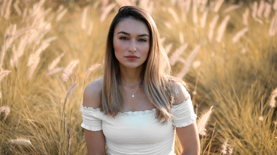 Woman in a white off-the-shoulder top in tall golden grass, before the Honey Glow LUT